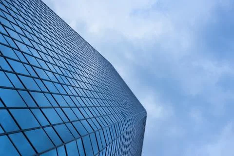 Cloudy blue sky reflection skyscraper glass exterior trees framing Stock Photos