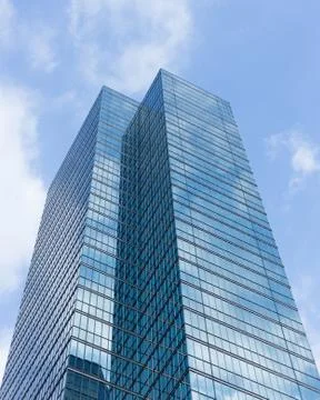 Cloudy blue sky reflection skyscraper glass exterior trees framing Stock Photos