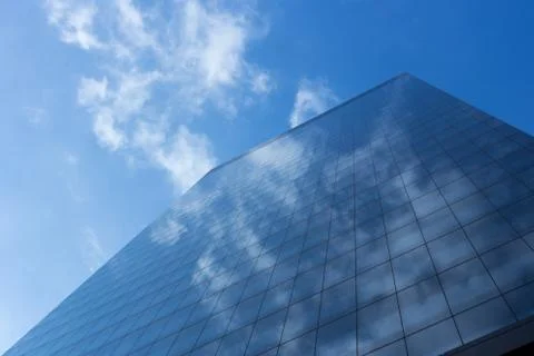 Cloudy blue sky reflection skyscraper glass exterior trees framing Stock Photos