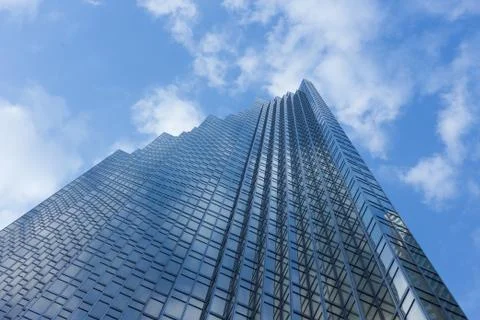Cloudy blue sky reflection skyscraper glass exterior trees framing Stock Photos