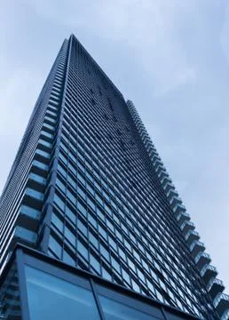 Cloudy blue sky reflection skyscraper glass exterior trees framing Stock Photos