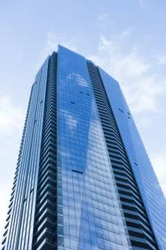 Cloudy blue sky reflection skyscraper glass exterior trees framing Stock Photos
