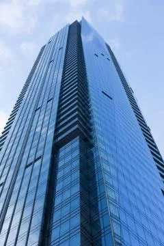 Cloudy blue sky reflection skyscraper glass exterior trees framing Stock Photos