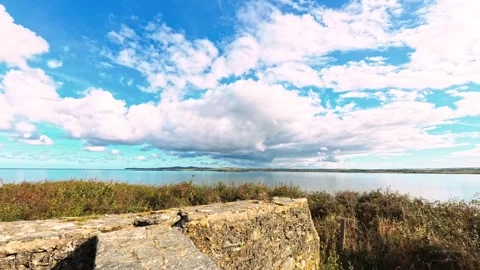 Cloudy blue sky time lapse approaching stone wall on Anglesey coast Видео 317644538