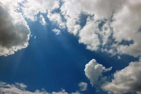 Cloudy, blue sky with white clouds and sunlight through them Stock Photos