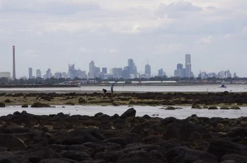 Cloudy day at a beach with cityscape Stock Photos