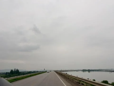 Cloudy day on a highway bridge over a river. Stock Photos