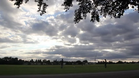 Cloudy day at a park with silhouette of trees and people playing catch timelapse Stockbeeldmateriaal 141484902
