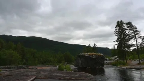 Cloudy day at the river with a large rock and trees in Norway during summer.. Stock Footage 340201619