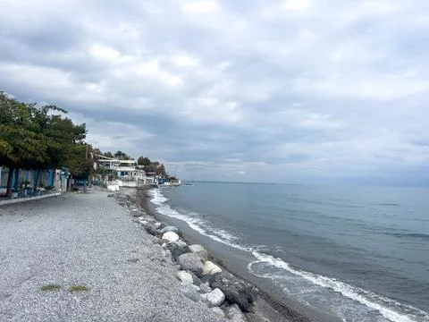 Cloudy day at serene pebble beach with calm ocean waves Stock Photos