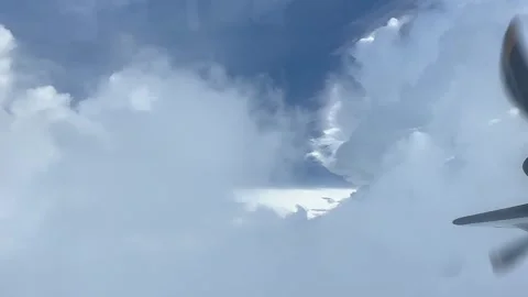 Cloudy day time sky through flying plane window sun flair  aircraft propellor Stock Footage 248960019