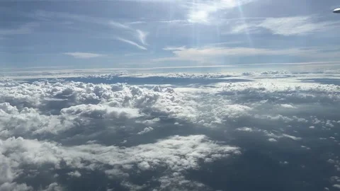 Cloudy day time sky through flying plane window sun flair aircraft Stock Footage 248960024