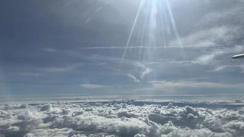 Cloudy day time sky through flying plane window sun flair aircraft Stock Footage 248960037