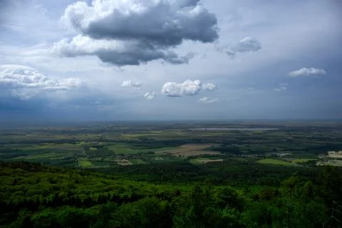 Cloudy day view from hilltop over green fields. Stock Photos