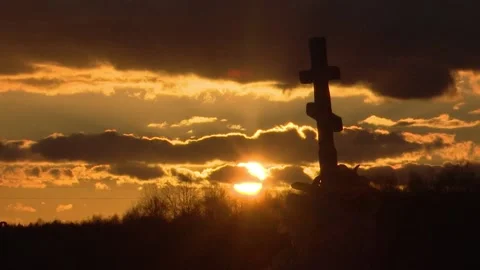 Cloudy evening sky and the setting sun, the silhouette of an old stone cross. Video stock 150256972