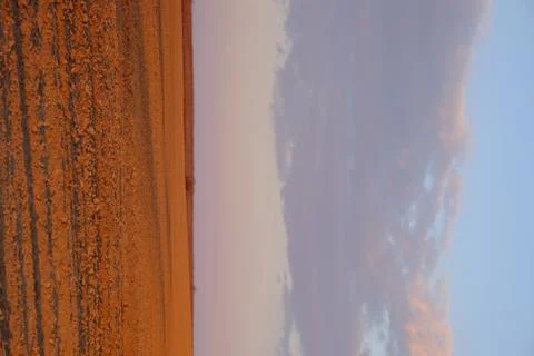 Cloudy evening sky over an empty agricultural field. Bright sunset landscape. Stock Photos