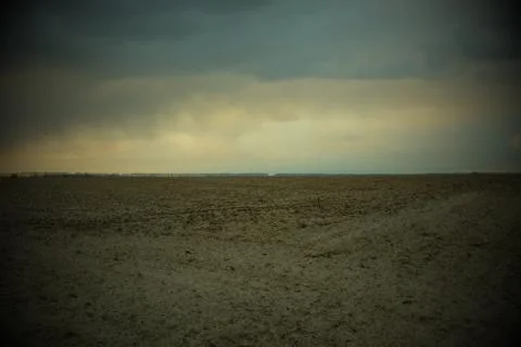 Cloudy evening sky over a plowed farm field. Landscape. Vignette Stock Photos