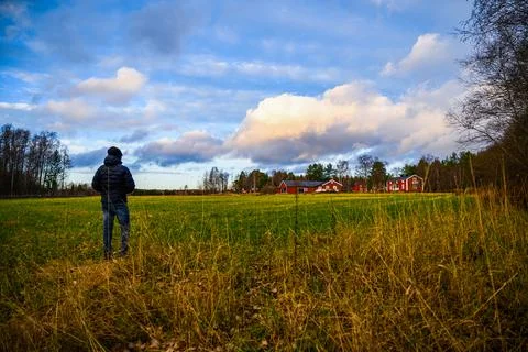 A cloudy landscape view of open field filled with grass with red wooden cotta Stock Photos