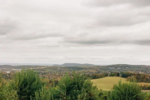 Cloudy landscape view of rolling hills and trees during fall season in a rural Stock-Fotos