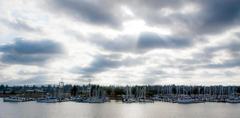 Cloudy marina with sun rays Stock Photos