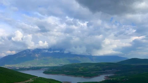 Cloudy mountain landscape with layered sky and green hill shadows Stock Footage 310246200