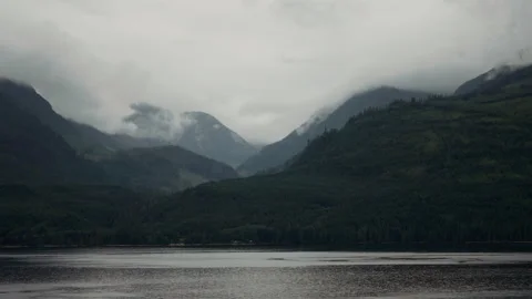 Cloudy mountain valley above a forested shoreline in Alaska Video stock 347824767