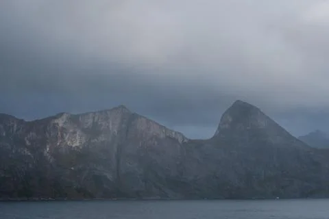 Cloudy mountainscape. Steep cliffs and one spiky peak. Stock Photos
