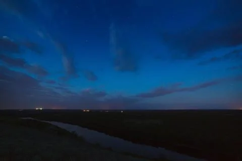 Cloudy night sky over the river before dawn. Stock Photos
