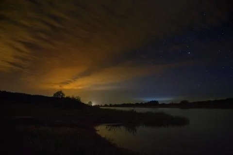 Cloudy night sky over the river before dawn. Stock Photos