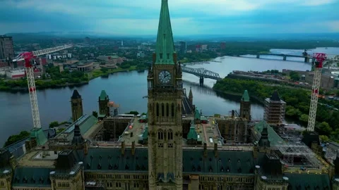 Cloudy Parliament Hill clock tower with Canadian flag flutters aerial in Stock Footage 331274874