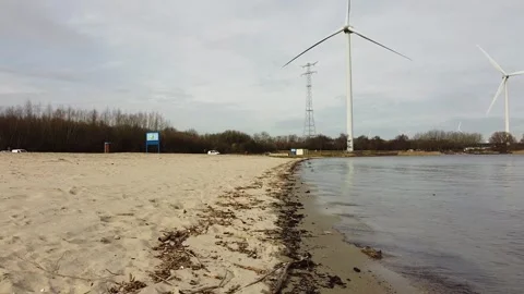 Cloudy sand beach with windmill en short waves. Stock Footage 303082135