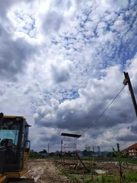 Cloudy skies, fields and bulldozer Stock Photos