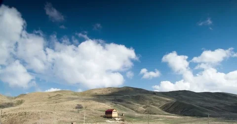 Cloudy sky above the house in the hilly valley Stock Footage