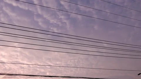 Cloudy sky and electric wires that are reflected into pink-purple by the sun in  Stock Footage 159841999