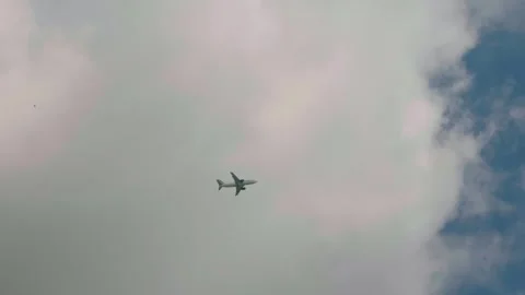 Cloudy sky and high-rising plane flying away as seen from below. Video stock 296387953