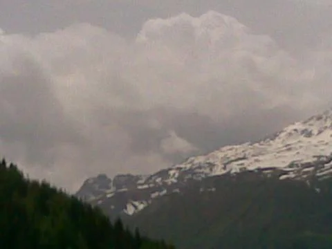 Cloudy sky and snow-capped mountains Stock Photos