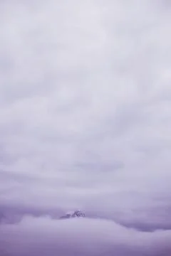 Cloudy sky and a summit in purple tone Stock Photos