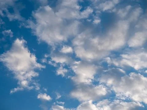 Cloudy sky background with soft white clouds scattered over blue sky Stock Photos