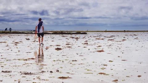 Cloudy sky on a beach with fishers on Noirmoutier island, France Stock Photos