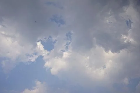 A cloudy sky with dramatic, dark grey cloud formations covering brighter white Fotos Stock