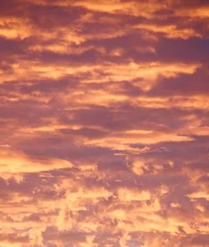 Cloudy sky during sunset with a saturated bright orange color Stock Photos