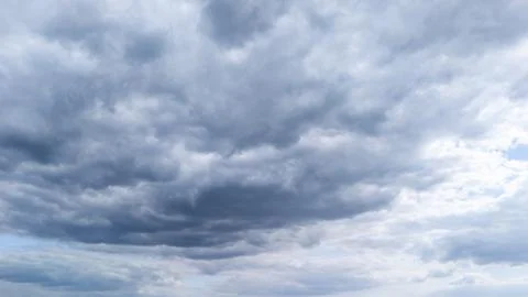 Cloudy sky with dynamic gray clouds above a serene landscape, creating a Stock Photos