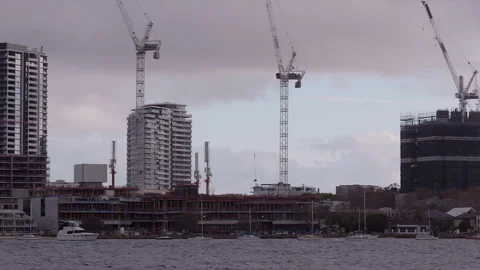 Cloudy sky frames riverside building constructions Cranes overhead. Skyscrapers  Video stock 252055011