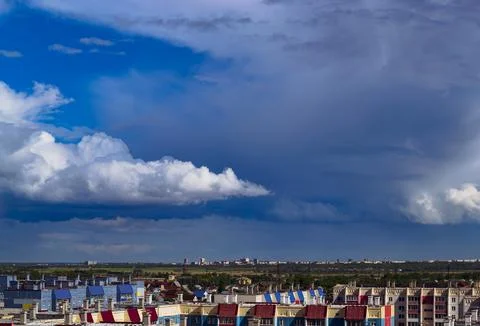 A cloudy sky hangs over the roofs of houses and the city in the distance Stock Photos