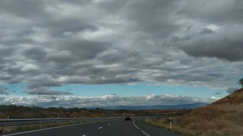 Cloudy sky on a long stretch of road Stock Photos