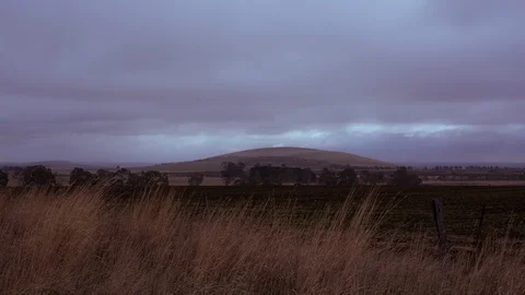 Cloudy sky moving over mountain and field at dusk Stock Footage 94884649