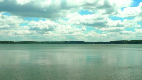 Cloudy sky over the lake with reflections and distant trees Stock Footage 339438110