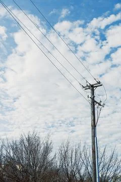 Cloudy sky over power lines and bare trees in a rural setting during daytime Stock Photos