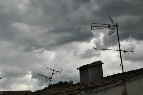 Cloudy sky over the roofs of a town Stock Photos