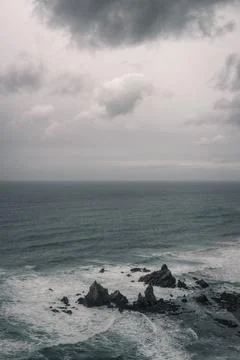 Cloudy sky over the rugged rock formations of a beach Stock Photos